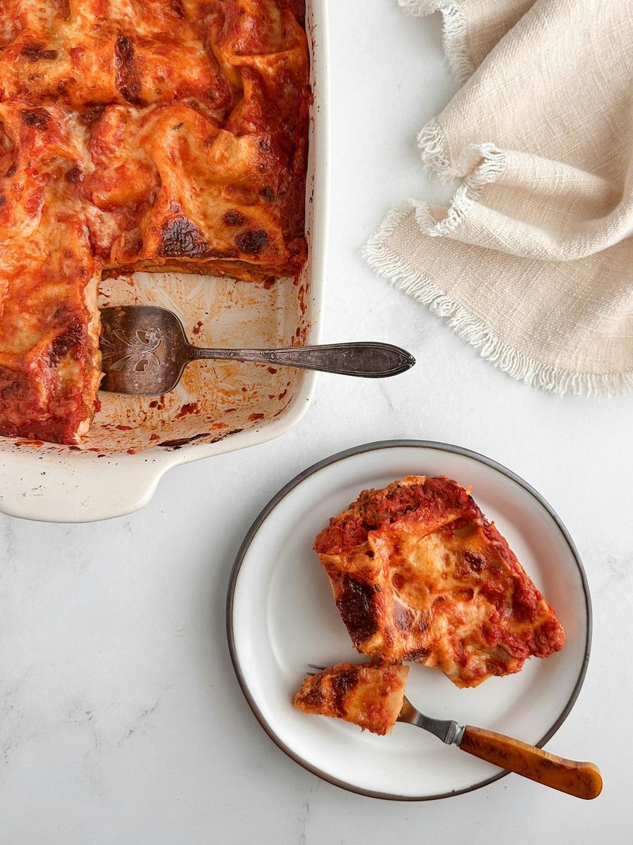 Lasagne appena sfornate nella teglia e una porzione nel piatto