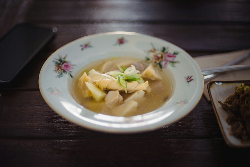 Scodella di brodo chiaro con pasta ripiena e un cucchiaio